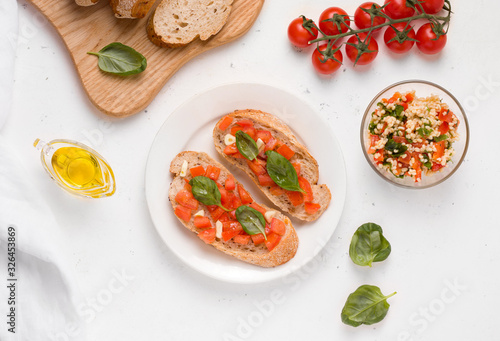 vegan breakfast on a white plate of sandwich with tomato and bruschetta basil and salad