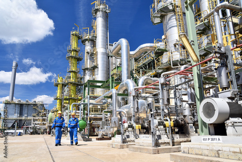 chemical industry plant - workers in work clothes in a refinery with pipes and machinery