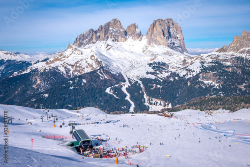 View of a ski resort piste with people skiing in Dolomites in Italy. Ski area Belvedere. Canazei, Italy