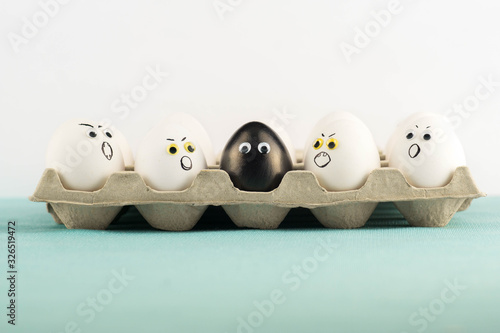 Black egg among angry, prejudiced white eggs attacking the black one. Xenophobic, racist concept. Black lives matter.