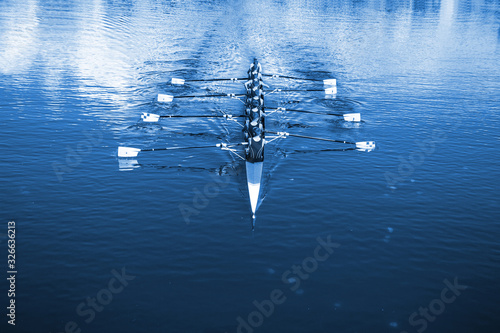 Boat coxed eight Rowers rowing on the tranquil lake. Classic Blue Pantone 2020 year color.
