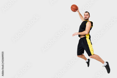 Side view of man posing mid-air while dunking with copy space
