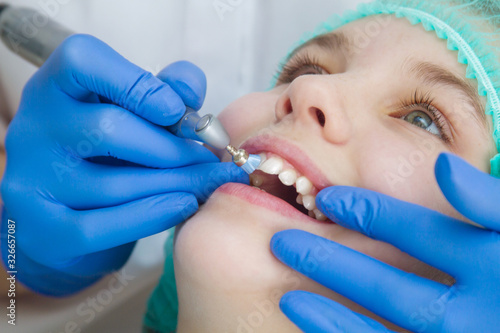 A woman dentist doctor brushes the teeth of a teenage child with a special medical brush. Inspection of the oral cavity of the girl. Modern technologies in dentistry.