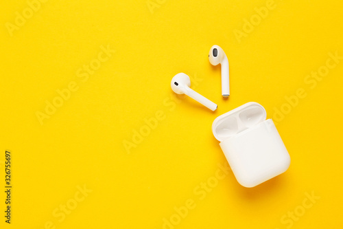 White wireless earphones on yellow background