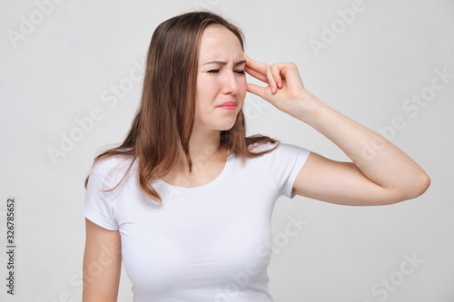 A girl in a white T-shirt is tormented by dizziness and disorientation.