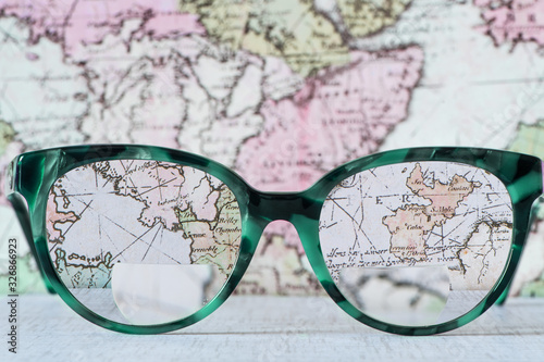 Eyeglasses Glasses with Bifocals and Black Blue Frame smudged Fashion Vintage Style on Wood Desk with world map background. 