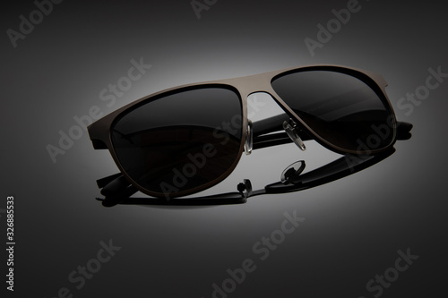 Sunglasses on a black gradient, matte background, shallow depth of field. The concept is stylish and beautiful.
