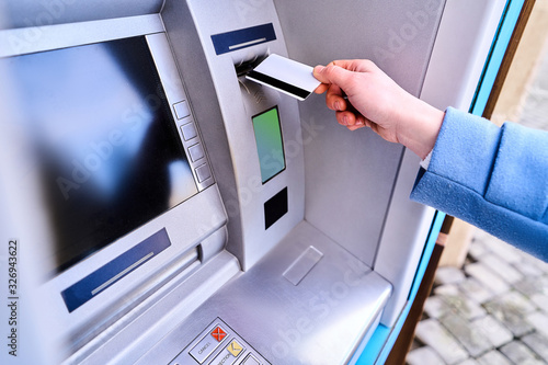 Person insert plastic credit card into street atm bank to withdrawing money