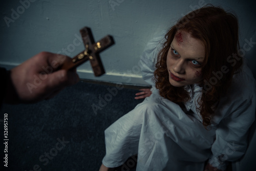 exorcist holding cross in front of obsessed girl