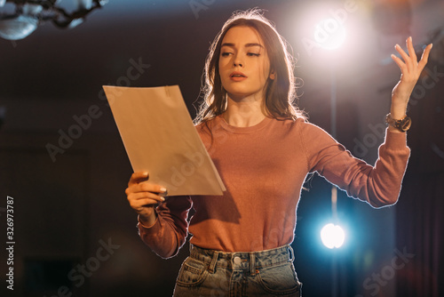 young actress reading scenario on stage in theatre