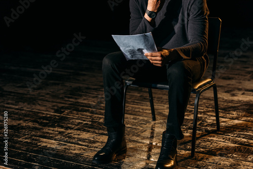 cropped view of african american actor holding scenario on stage during rehearse