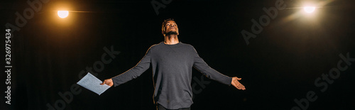 panoramic shot of african american actor holding scenario and standing on stage during rehearse