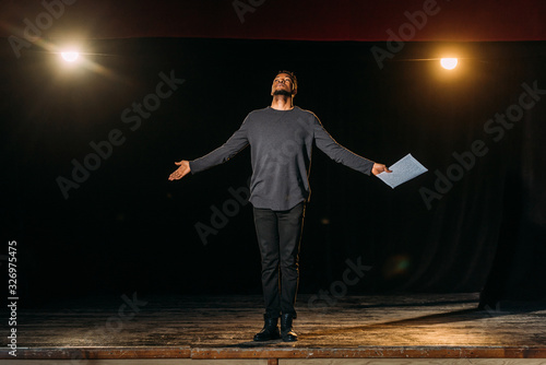 african american actor holding scenario and standing on stage during rehearse