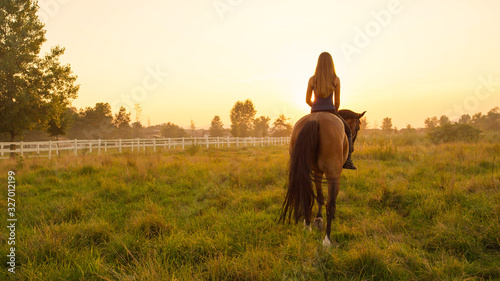 Pretty young blonde girl bareback riding towards rising sun
