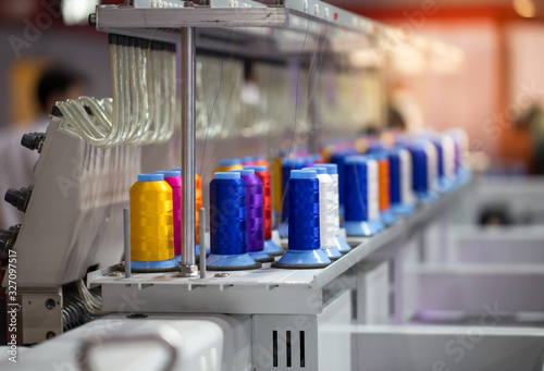 Colorful rows spools of thread stand on embroidery machine