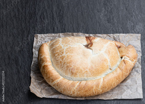 Homemade cornish pasty on black stone background