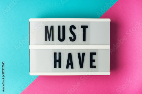 Must have - text on a display lightbox on blue and pink background.