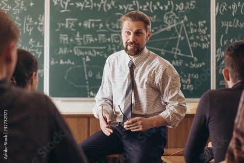 Cheerful bearded professor having a casual informal conversation with students during math seminar