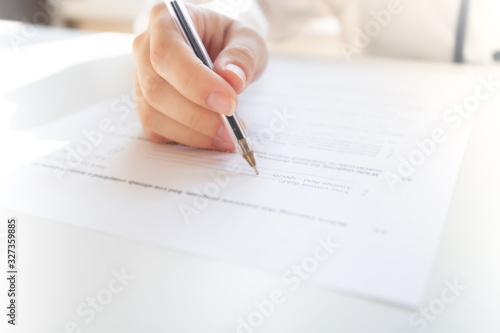 Female hands write with a pen on a sheet of paper, fill out a questionnaire