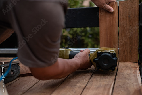 Hand man carpenter using air nail gun to complete wood table in garden