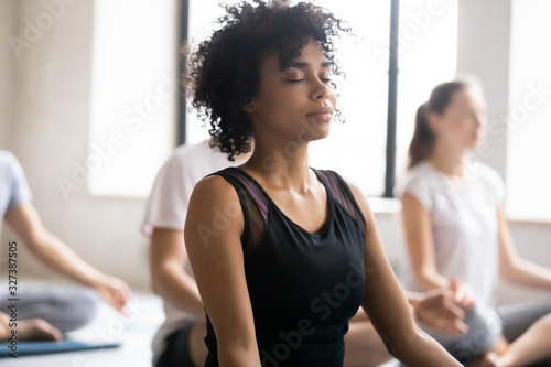 African female closed eyes do meditation practice with associates