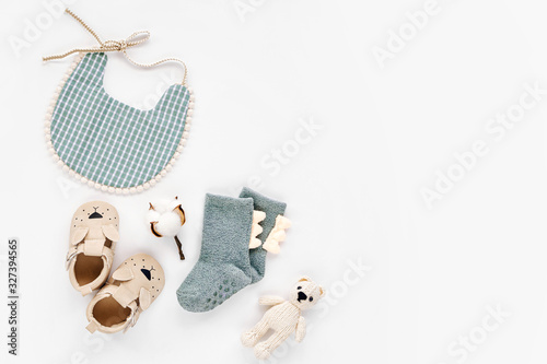 Bib, socks, toy and cute baby slippers for boy. Set of newborn clothes and accessories. Flat lay, top view