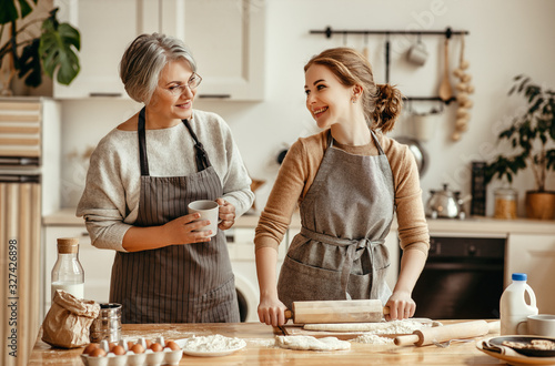 happy family grandmother old mother mother-in-law and daughter-in-law daughter cook in kitchen, knead dough, bake cookies.