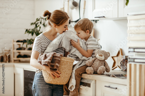 Happy family mother housewife and child in laundry with washing machine .