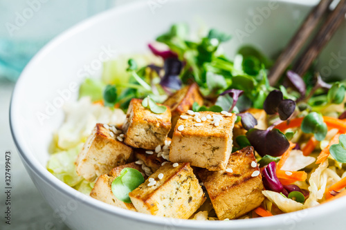 Fried tofu salad with sprouts and sesame seeds in white bowl. Vegan food, asian food concept.