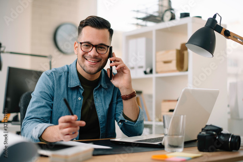 Businessman in office. Handsome man talking on phone at work.