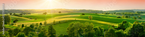 Panoramic landscape with beautiful green hills and warm sunshine illuminating the fields