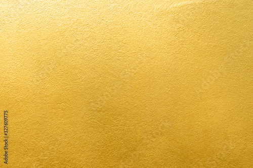 Gold wall texture background. Yellow shiny gold foil paint on wall surface with light reflection