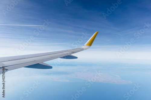 ala de avión de pasajeros airbus a320 sobrevolando el delta del ebro (cataluña, españa), con el cielo zul nublado de fondo.