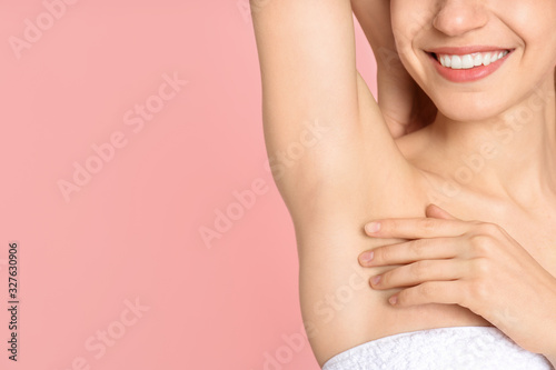 Young woman showing armpit with smooth clean skin on pink background, closeup. Space for text