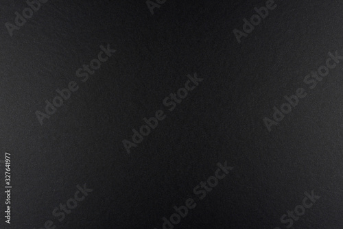 Black background made of real black paper with a matt fibrous structure, illuminated by a soft light on the sides.