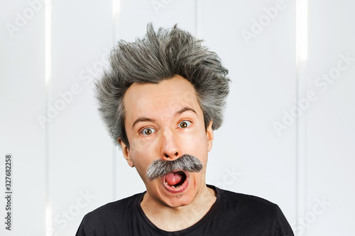 Portrait of jocular aging man with grey long hair sticking his tongue out in Einstein manner.