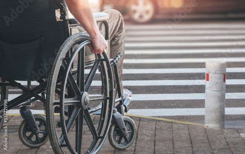 Disablee man on wheelchair crossing the road.