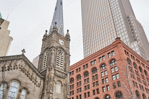 The Old Stone Church in Cleveland Ohio, dwarfed by the nearby surrounding buildings and skyscrapers. It stands in the shadow of the Key Tower. The Romanesque architecture contrasts nearby buildings.