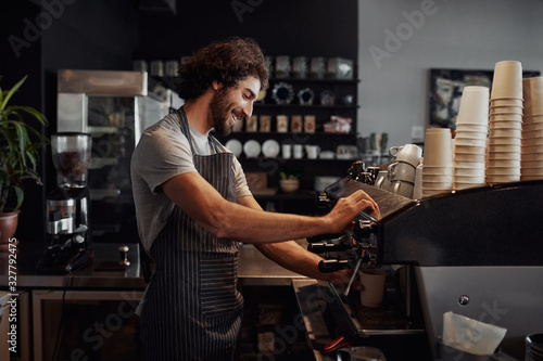 Smiling man with apron preparing coffee for customer in his small business