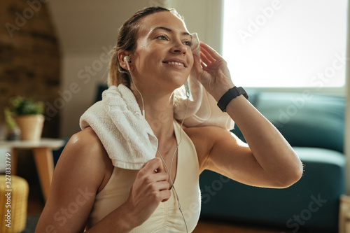 Young happy sportswoman wiping sweat with a towel on a break at home.