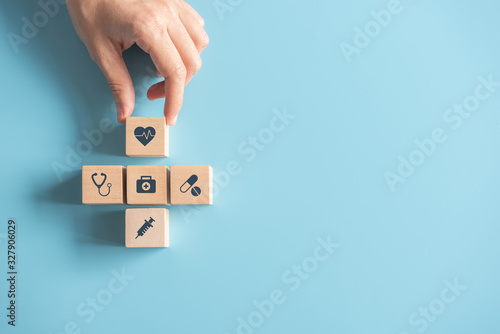 Health Insurance Concept, Hand of woman arranging wood cube stacking with icon healthcare medical on blue background, copy space.