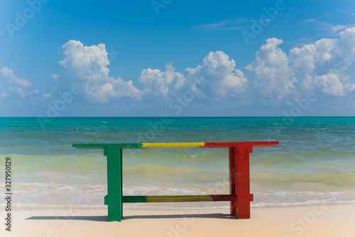 Reggae colors Wood Bench with Caribbean beach background