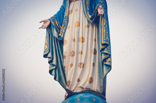 The blessed Virgin Mary statue figure in a sunset time. Catholic praying for our lady - The Virgin Mary. Hand closed-up.
