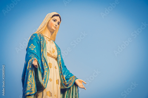 Close-up of the blessed Virgin Mary statue figure. Catholic praying for our lady - The Virgin Mary. Blue sky copy space on background.