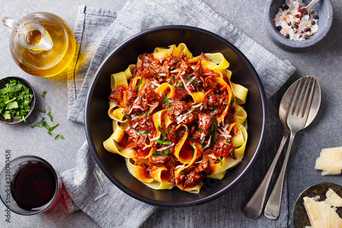 Pasta fettuccine with beef ragout sauce in black bowl. Grey background. Close up. Top view.