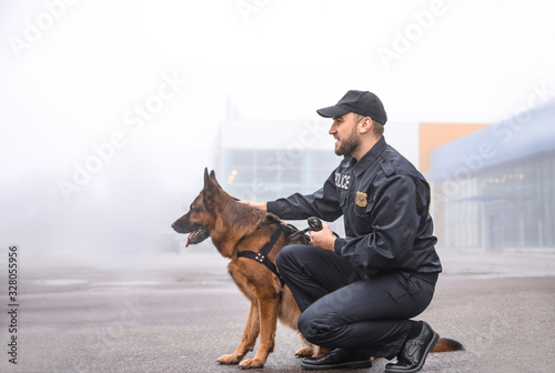 Male police officer with dog patrolling city street