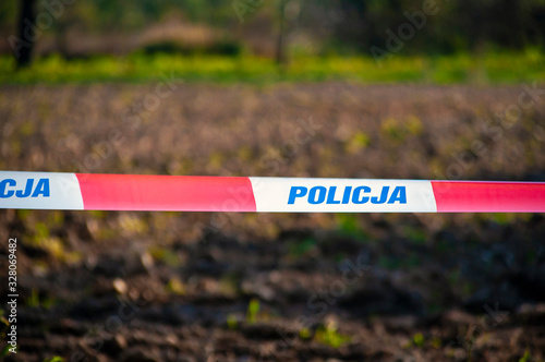 Red and white protection tape with "POLICJA" inscription. Polish police "do not cross" tape