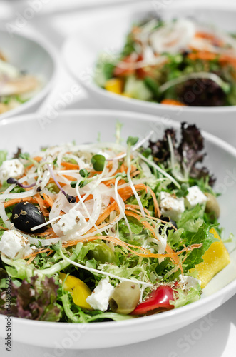 mixed fresh organic salads on white restaurant table