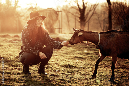 Giovane donna felice in campagna con una capra