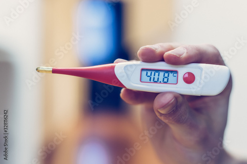 Flu and corona concept: Man is holding a fever thermometer in his hand, close up